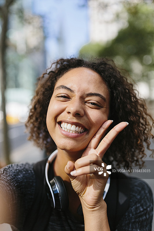 快乐的女人在城市里展示和平手势图片素材