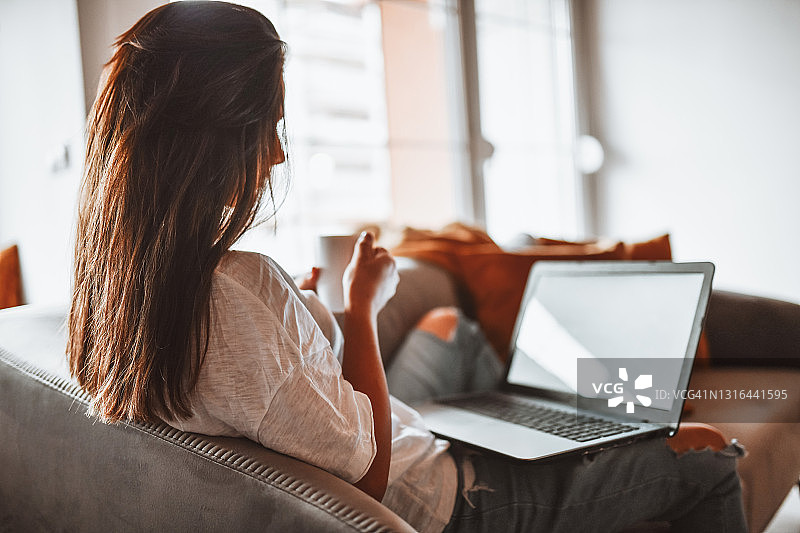 在家用笔记本电脑看电影喝茶的女人图片素材