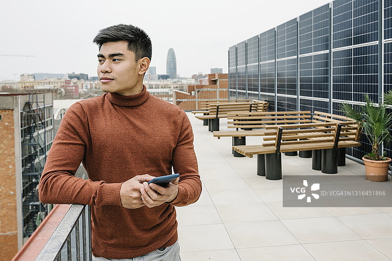 男企业家站在屋顶手持手机图片素材