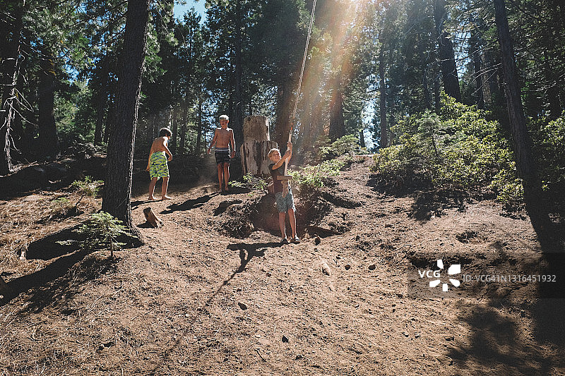 三个男孩尘土飞扬山坡玩秋千图片素材