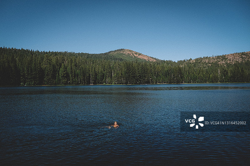 夏季男孩在湖里游泳的远景小图图片素材