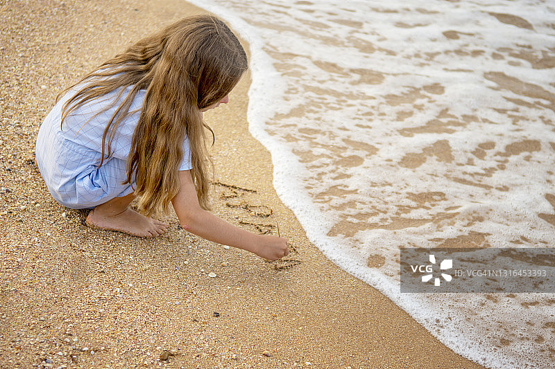 在海边沙滩上写信的女孩图片素材