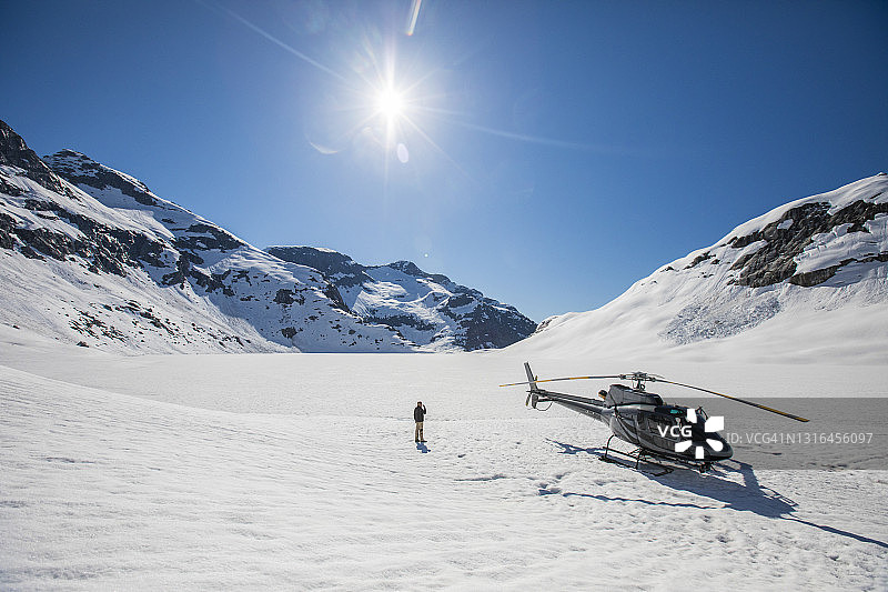 男人站在直升机旁眺望壮丽山景图片素材