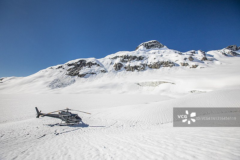 在加拿大不列颠哥伦比亚省冰川上降落的直升机图片素材