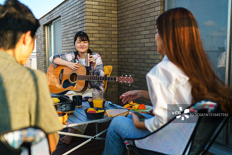 一群朋友在阳台上享受美食、饮品和音乐图片素材
