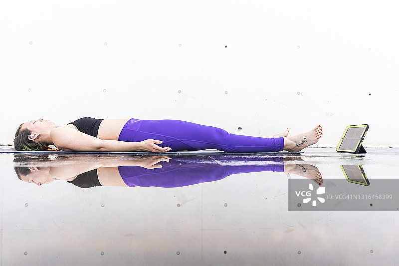 女运动员参加在线瑜伽课程，做摊尸式瑜伽动作图片素材