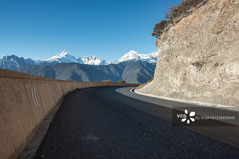 通往雪山的藏族聚居区高原上的空旷道路图片素材