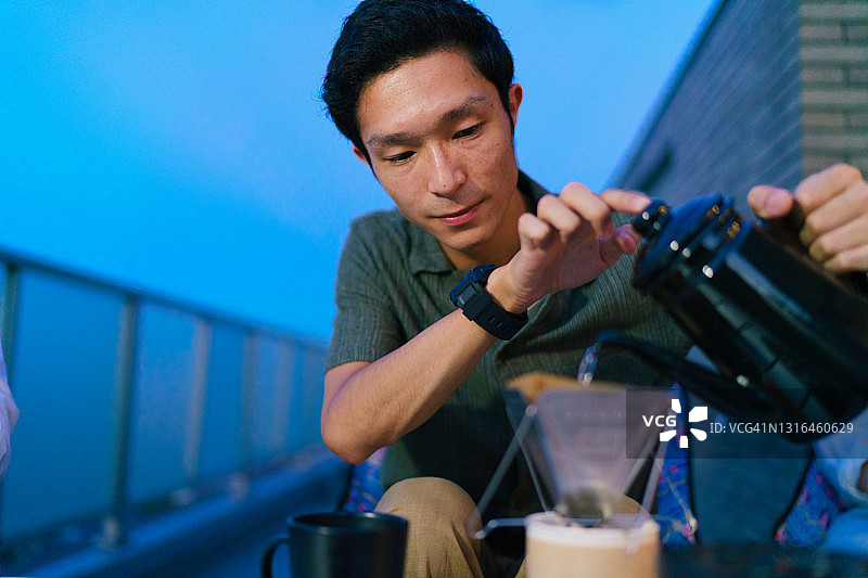 年轻男人晚上在阳台上准备咖啡图片素材