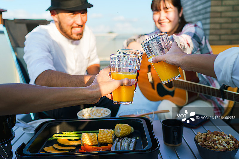 一群朋友在阳台上享受美食、饮品和音乐图片素材