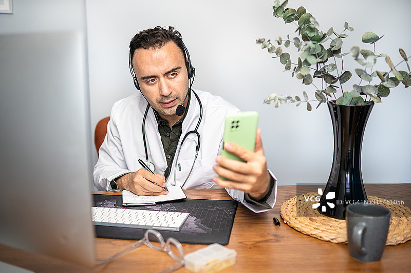 保持社交距离期间与患者进行视频通话的男医生图片素材