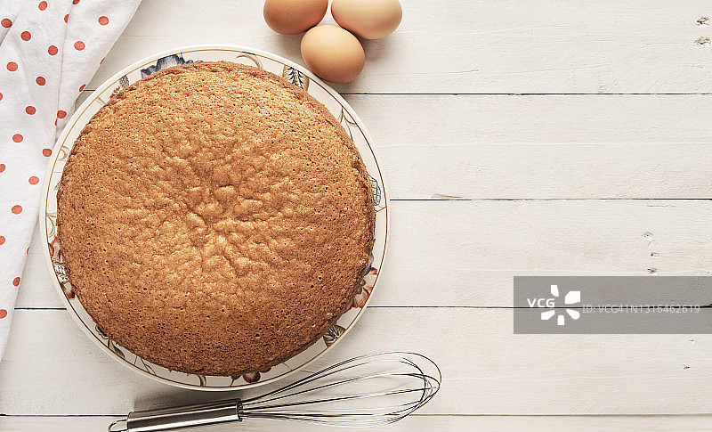 自制海绵蛋糕和鸡蛋俯视图，白色木桌图片素材