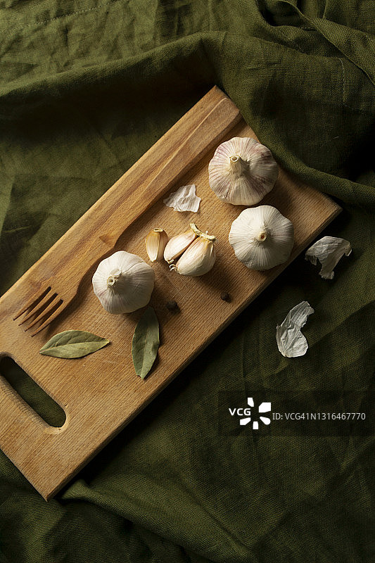 绿色桌布上木制砧板上的大蒜俯视图图片素材