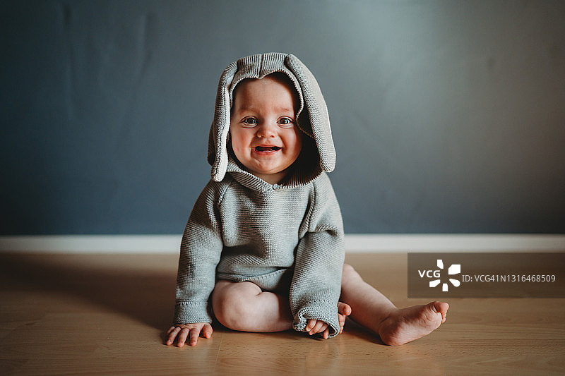 可爱的微笑宝宝穿着复活节兔子连体衣图片素材