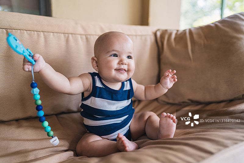 可爱婴儿坐在沙发上拿着玩具图片素材