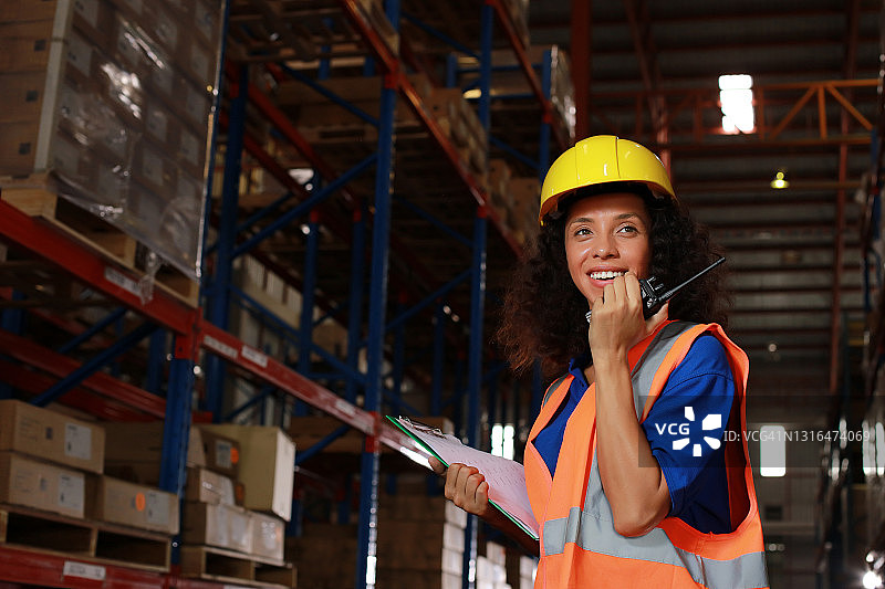 年轻女性在仓库物流团队中使用无线电进行通信图片素材