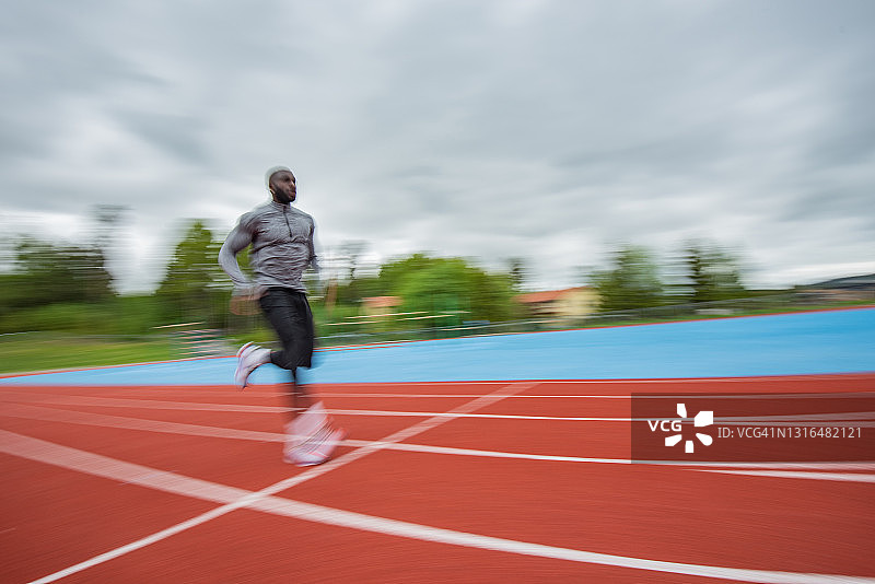 在赛道上跑步的年轻男运动员图片素材
