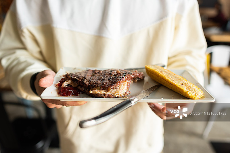 在餐厅里端着一盘肉的年轻男人图片素材