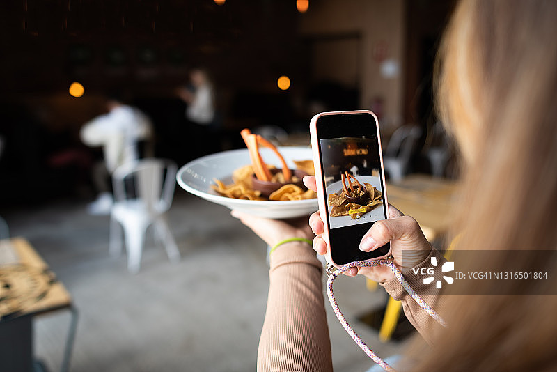 年轻女子用手机拍摄玉米片图片素材
