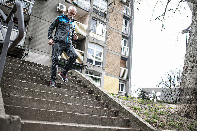 在城市社区楼梯上跑步的活力老年男人图片素材