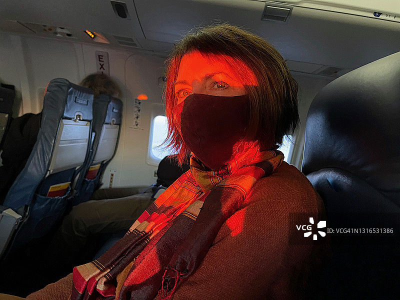 戴口罩的女人在日落时分的飞机上图片素材