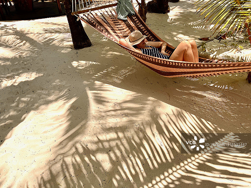 女子在海滩热带度假村的吊床上放松图片素材