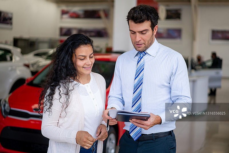 女人在汽车经销店买车并与销售员交谈图片素材