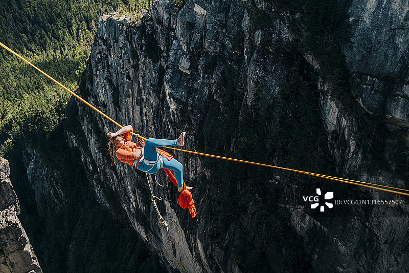 高空表演者在离地面很远的高空钢索下悬挂并整理她的丝绸图片素材