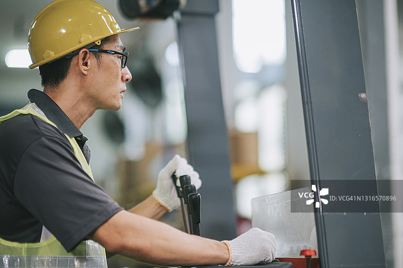 在工业工厂操作叉车的亚洲华人仓库工人侧视图图片素材