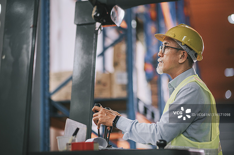 在叉车上清点库存的亚洲仓库老工人图片素材