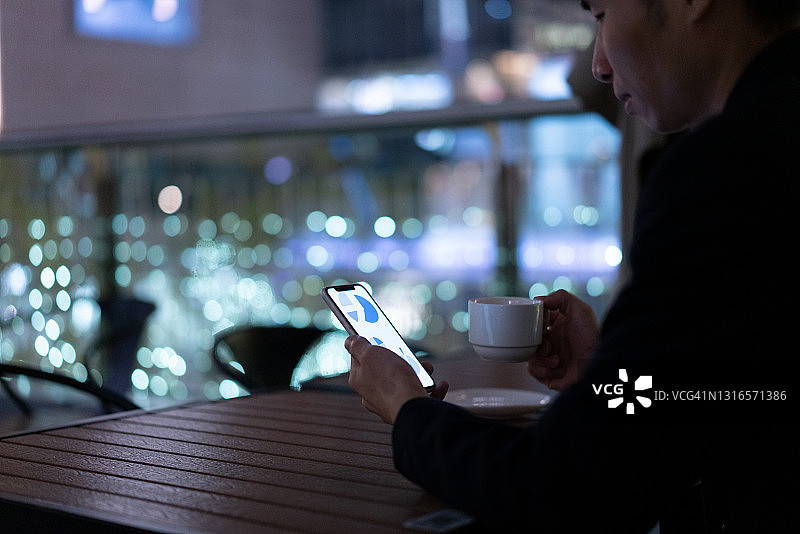 身穿西装的亚洲男人正在使用智能手机查看统计图表图片素材