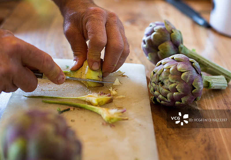 男人切新鲜朝鲜蓟手部特写图片素材