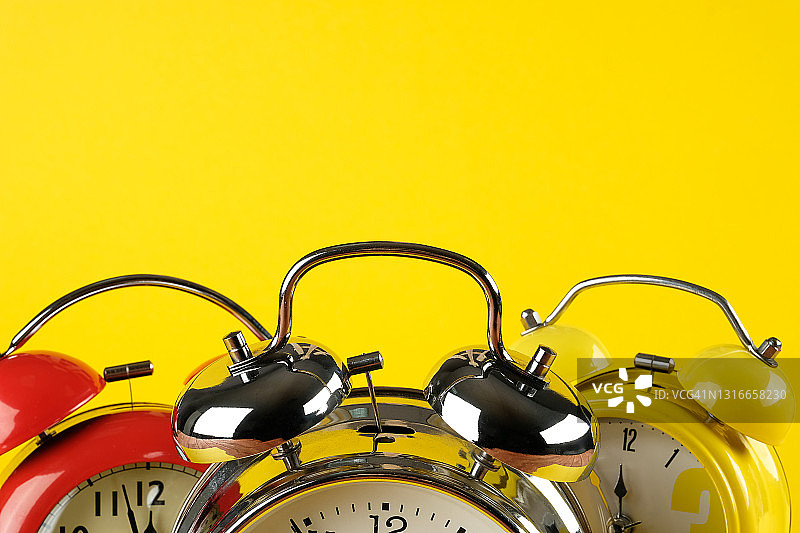 复古风格的彩色闹钟，明黄色背景，时间流逝的概念banner图片素材