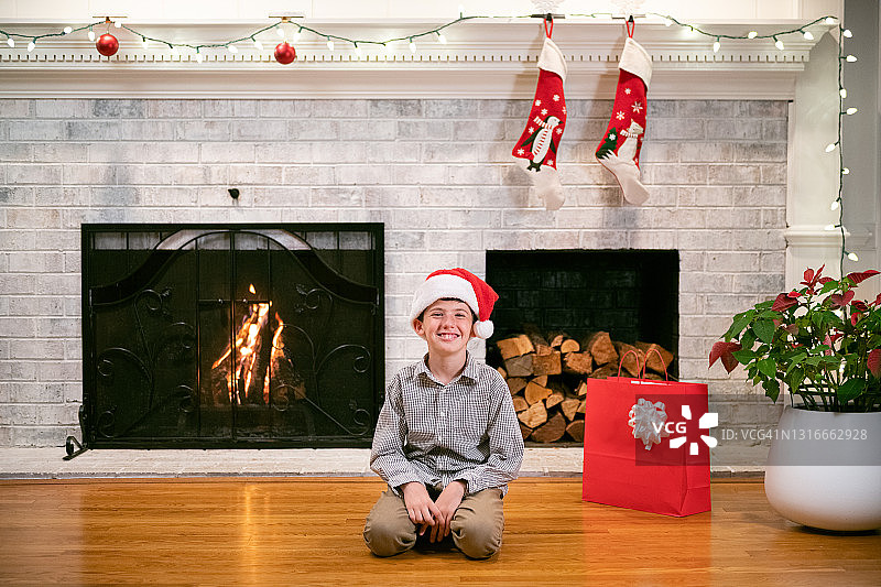 坐在圣诞装饰壁炉旁的男孩肖像图片素材