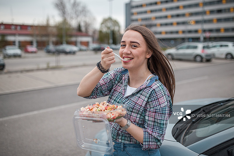 年轻女子享用塑料盒装沙拉图片素材