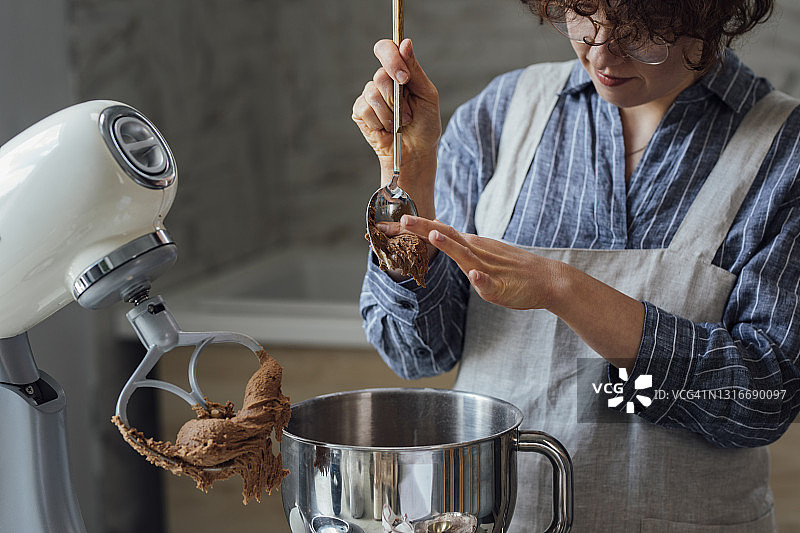 制作曲奇面团：女人在搅拌碗中混合配料图片素材