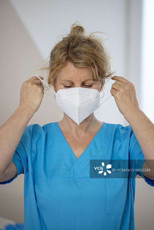 疫情期间中年女医生在诊室戴防护口罩图片素材