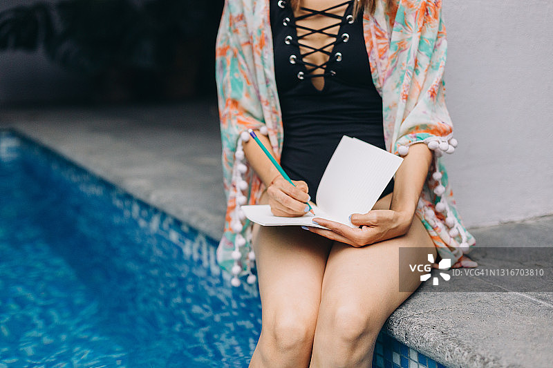 女人泳池边泡脚写日记图片素材