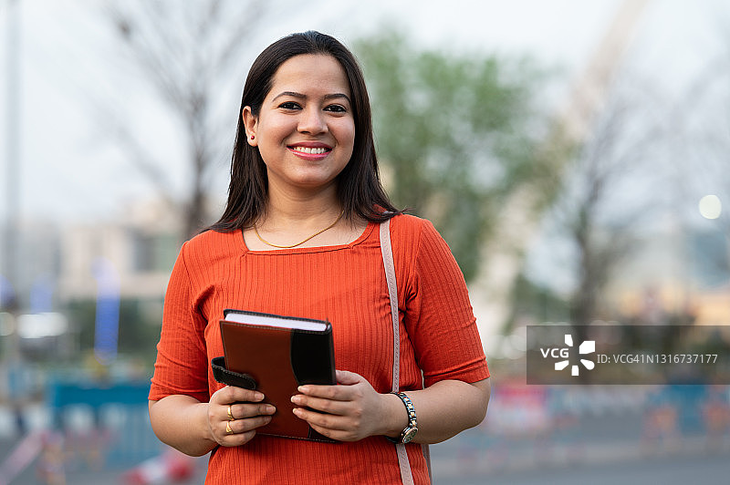 美丽的印度少女手拿书本看着镜头图片素材