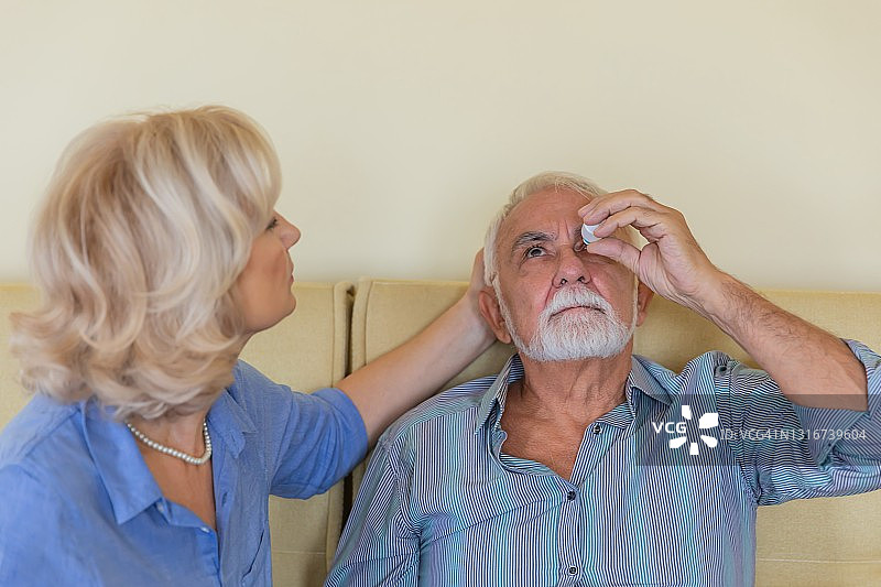 老人在妻子的帮助下使用滴眼液图片素材