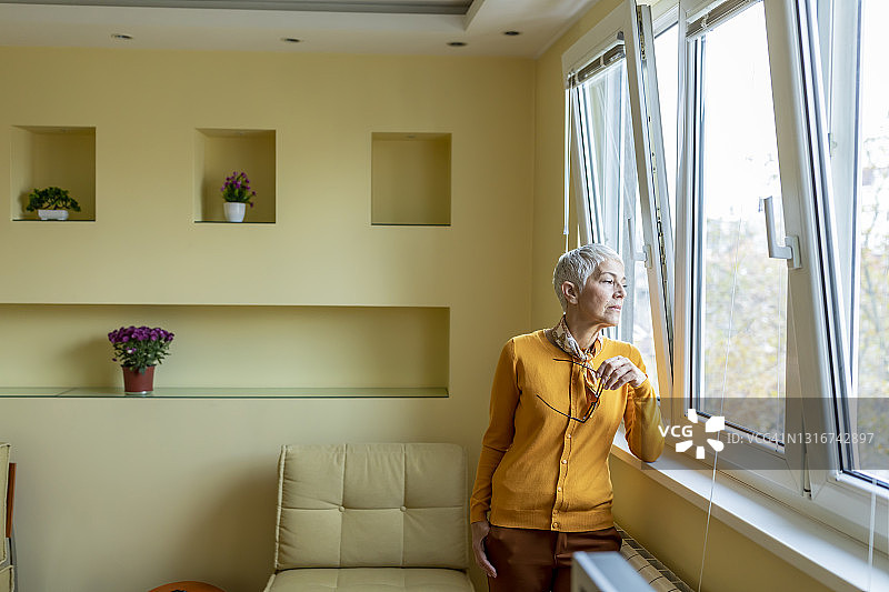 孤独的女人望着窗外，感到悲伤和沮丧。图片素材