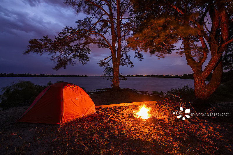 日落时分河岸帐篷旁的篝火：周末徒步图片素材
