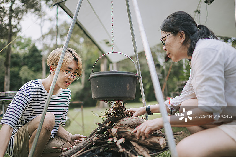 中国男孩和母亲在帐篷旁准备晚餐，生火煮汤图片素材