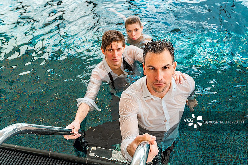 三位衣着整洁、刚从游泳池里出来的湿漉漉的人图片素材