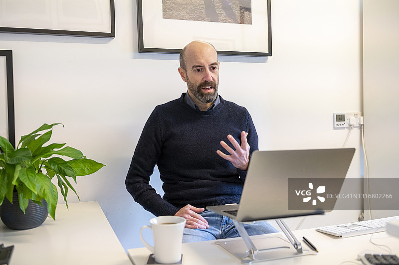 英国萨里：男子在家通过笔记本电脑参加线上会议图片素材