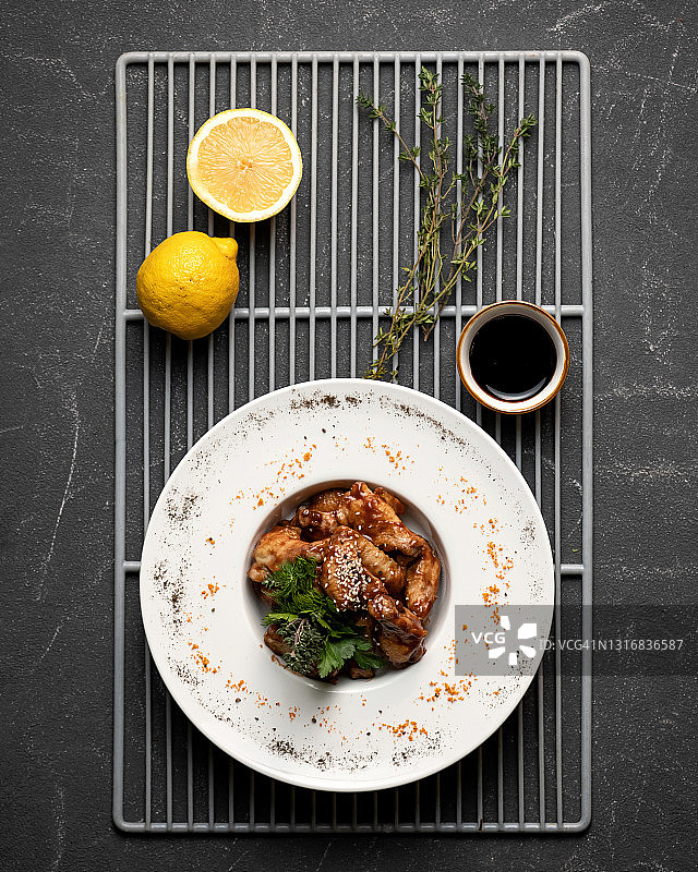 柠檬迷迭香烤鸡翅，丰盛午餐，黑色背景垂直4x5图片素材