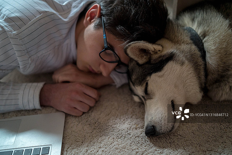 男人和他的狗在地板上工作图片素材