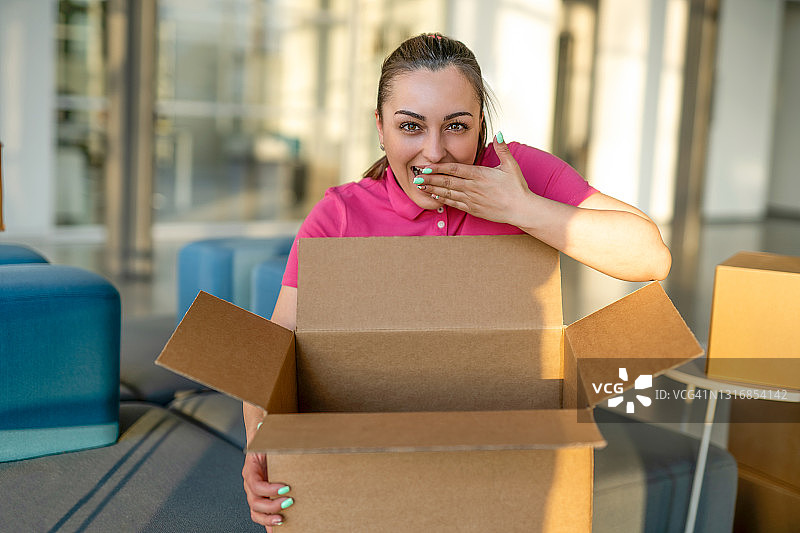 快乐微笑的女人打开纸板箱。网上购物概念图片素材