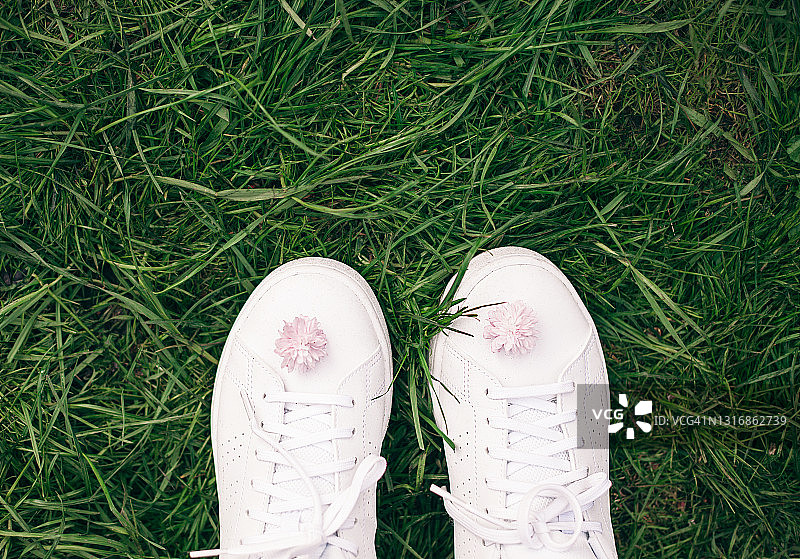 白色运动鞋特写，粉色樱花点缀，绿草背景，春季概念图片素材