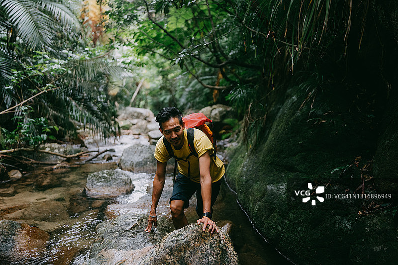 男子在日本冲绳丛林中的河流中徒步旅行图片素材