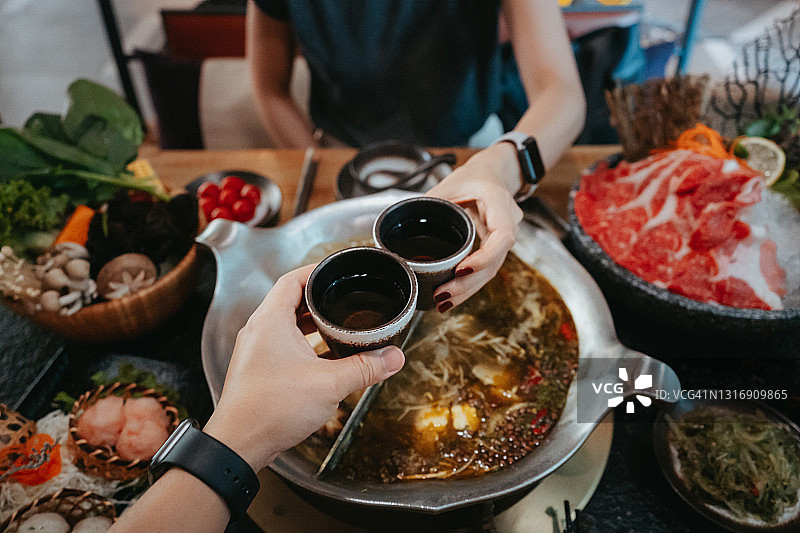 情侣享用中国火锅，举杯庆祝的美好时光图片素材